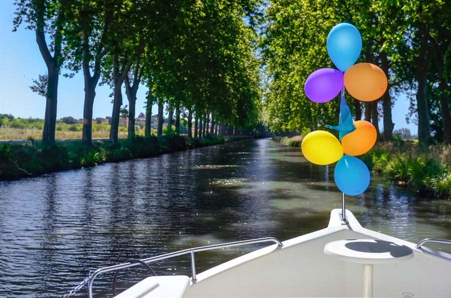 Bow of a self-drive canal boat on a tree-lined French canal